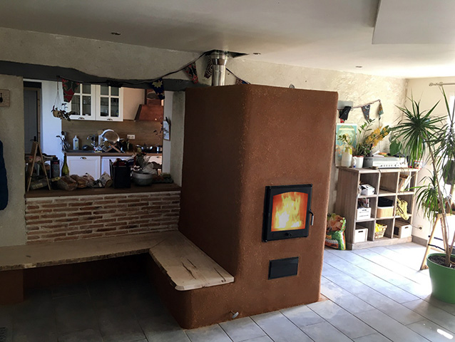 Poêle de masse avec enduit terre et banc chaud et alcoves